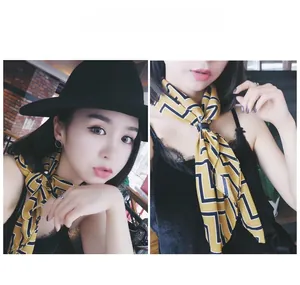 Detail of yellow geometric silk scarf with maze pattern and black ring buckle accessory