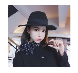 Detail of a chic black wide-brim felt hat with a stylish polka dot silk scarf accessory