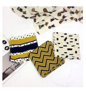 Flat lay detail showing a collection of patterned cotton-linen square scarves and diamond rings