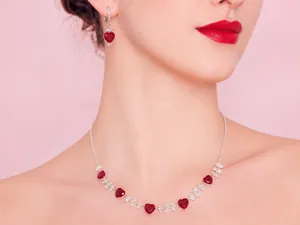 Detailed view of silver necklace and earrings set featuring vibrant red heart pendants