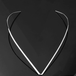 Close-up of polished silver V-shaped choker necklace on a reflective black surface