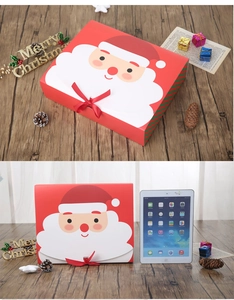 Close-up of red Santa Claus gift box with iPad for size comparison on a wooden table