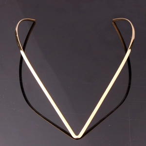 Macro shot of minimalist gold V-shaped rigid neck choker on a reflective surface