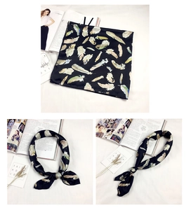 Dettaglio di un foulard in seta con stampa di piume colorate su base nera e trama liscia