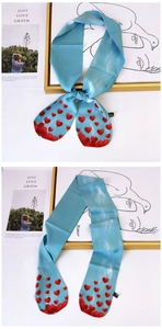 Detail of light blue silk scarf featuring red heart patterns and smooth twill texture