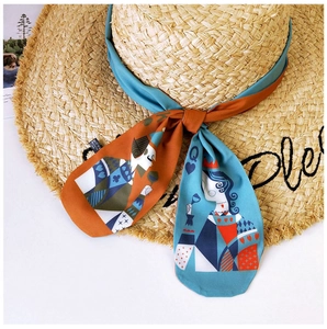 Detail of straw sun hat with frayed edge and queen-patterned silk ribbon scarf
