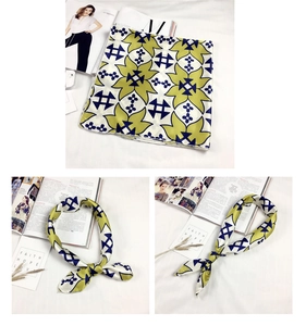 Dettaglio foulard in seta con motivi floreali gialli e geometrici blu su base crema