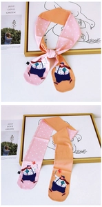 Close-up of a women's Twilly silk scarf with cartoon illustrations and polka dot patterns