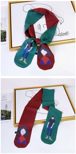 Detail of a narrow silk scarf featuring retro character illustrations and contrast colors