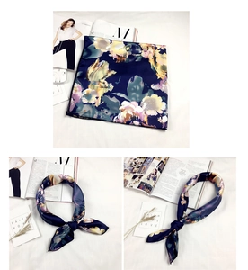Dettaglio di un foulard in seta blu scuro con motivo floreale giallo su letto bianco