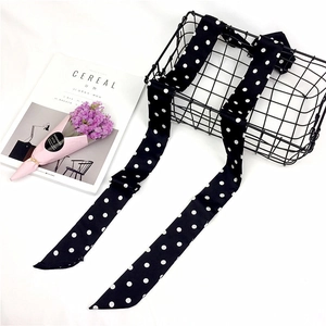 Close-up of elegant black and white polka dot silk scarf draped over a wire basket