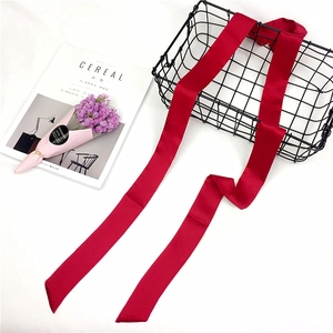 Long wine red satin scarf with glossy finish draped over a black iron wire basket