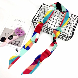 Detail of multi-color geometric print narrow silk scarf draped over a black wire basket