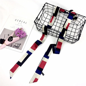 Close-up of geometric color block long scarf draped over a basket with floral decor