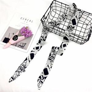 Long silk scarf with black and white artistic pattern placed on an elegant background