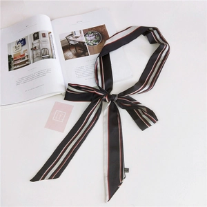 Close-up of elegant black silk-feel skinny scarf with stripes and garment care label