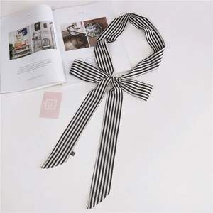 Detail of a black and white striped silk scarf tied in a bow with stylish magazine props
