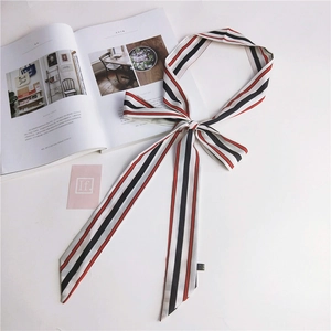 Close-up of red, black, and white striped narrow twilly scarf tied in a bow