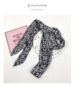 Detail of long black and white geometric chain pattern silk scarf on elegant white background