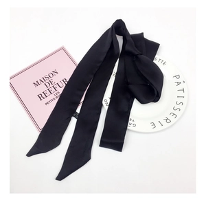 Detail of solid black silk skinny scarf featuring smooth texture and premium stitching
