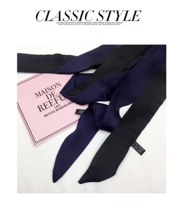 Detail of navy and black narrow satin scarves with high-gloss finish and sewn labels