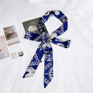 Detail of navy blue twilly scarf with white chain print on white fabric and magazine