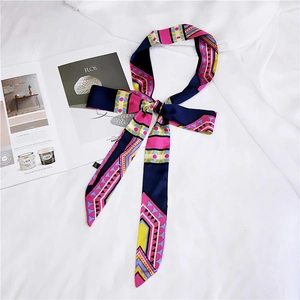 Detail of bohemian geometric silk scarf tied in a bow on a white bed with magazine