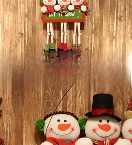 Close-up of three plush snowmen holding a Let It Snow sign with red plaid scarves