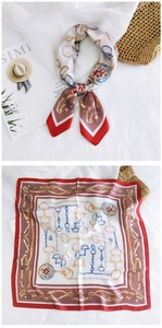 Detail of red and white satin square scarf featuring classic equestrian chain and horsebit patterns