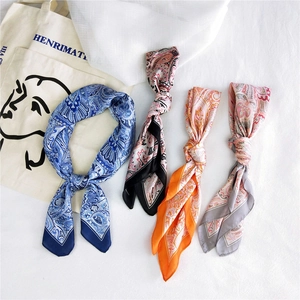 Flat lay of four paisley pattern silk scarves in blue, pink, orange, and grey colors