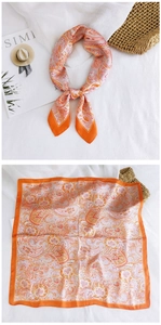 Detailed flat lay of a silk-feel square scarf featuring orange paisley prints and borders