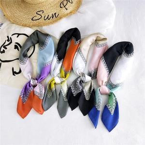 Flat lay of diverse chain patterned silk scarves with sun embroidery straw hat detail