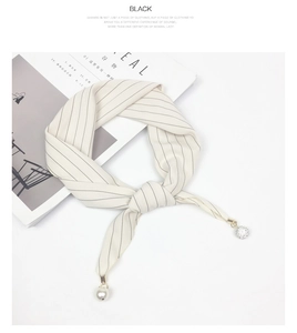 Detailed macro view of striped silk scarf featuring elegant pearl and crystal pendants