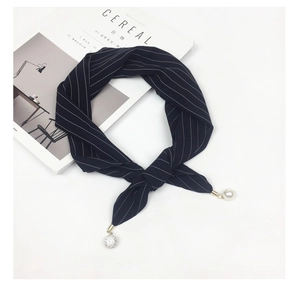 Detailed macro view of navy striped scarf featuring pearl and rhinestone ball pendants