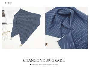 Detailed close-up of blue striped silk scarf with elegant pearl charms on a soft surface