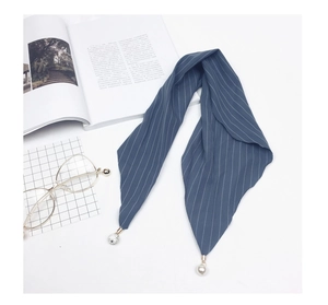 Detailed close-up of blue striped silk scarf featuring pearl and rhinestone ball pendants