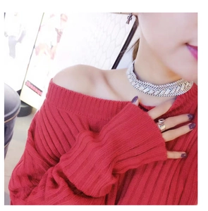 Detail of red off-shoulder ribbed knit sweater with rhinestone necklace and accessories