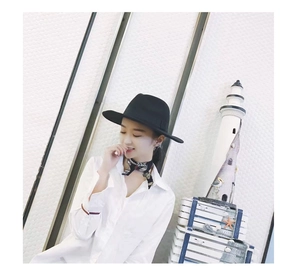 Styling detail of a black-and-white checkered silk scarf with a wide-brimmed felt hat