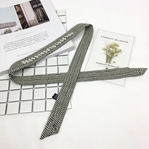 Elegant herringbone skinny silk scarf with rhinestones displayed on a fashion magazine