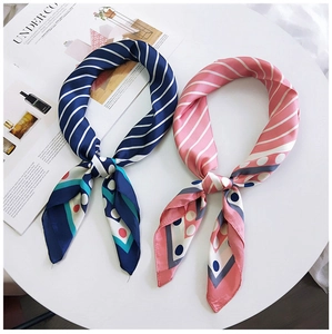 Détail de foulards en soie bleu marine et rose avec motifs rayés sur table blanche