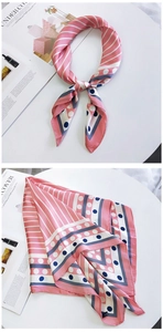 Détail d'un foulard en soie rose avec pois marine et rayures blanches sur fond épuré