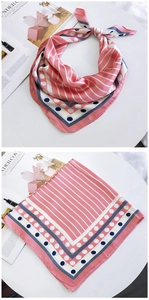 Détail d'un foulard en soie rose à rayures avec bordure à pois bleu marine et fini soyeux