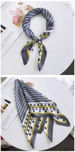Détail d'un foulard en soie avec motifs rayés gris et jaunes sur une table blanche