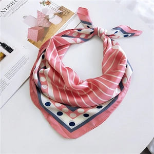 Carré de soie rose à rayures et pois bleus posé sur table blanche avec magazine
