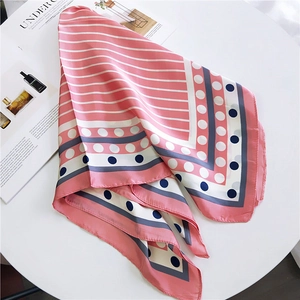 Carré de soie rose à rayures et motifs à pois sur une table blanche pour femme