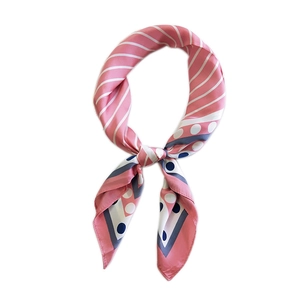 Foulard en soie rose à rayures et motifs géométriques noué de façon élégante