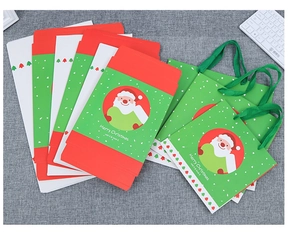 Flat lay of Merry Christmas gift boxes and paper bags with Santa and tree motifs