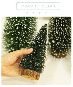 Miniature flocked Christmas tree with snow detail on rustic wood base held in hand