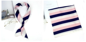 Détail d'un foulard en soie à rayures roses et marine avec boucle et accessoires déco