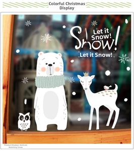 Close-up of Christmas window stickers featuring white bear, giraffe, and snow motifs